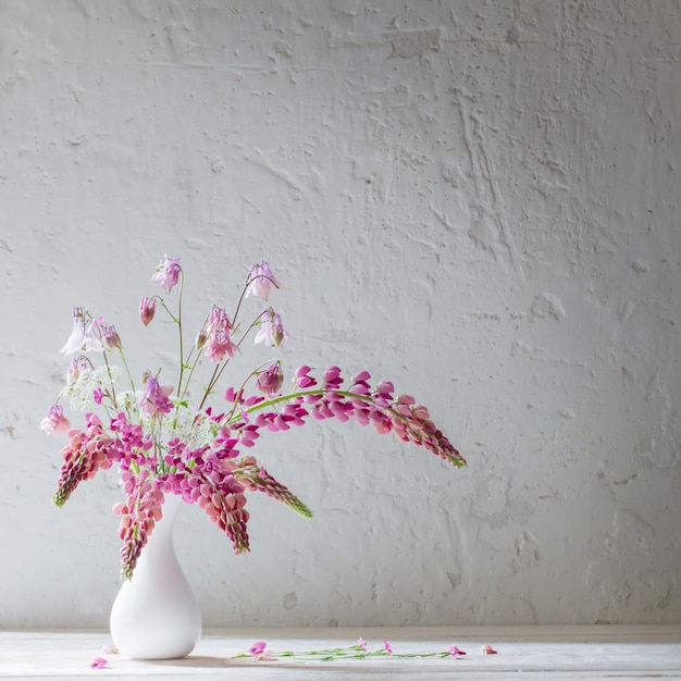 Roze zomerbloemen in witte vaas op witte oude achtergrond