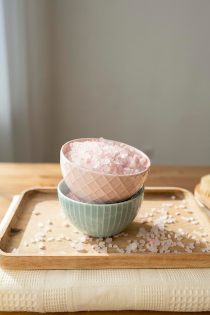 Roze zout in een kom op een dienblad met een handdoek op tafel