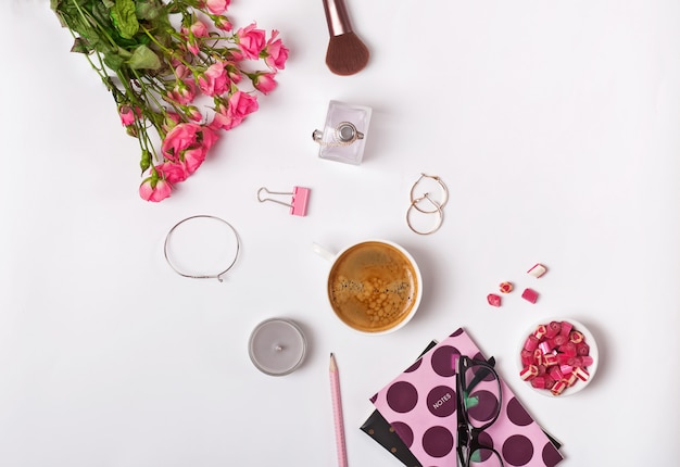 Rozen, koffie en kleine stylush vrouwelijke accessoires op de witte achtergrond