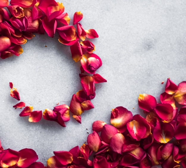 Rozenblaadjes op marmeren achtergrond bloemendecor en bruiloft flatlay vakantie wenskaart achtergrond voor uitnodiging voor evenement plat lag ontwerp