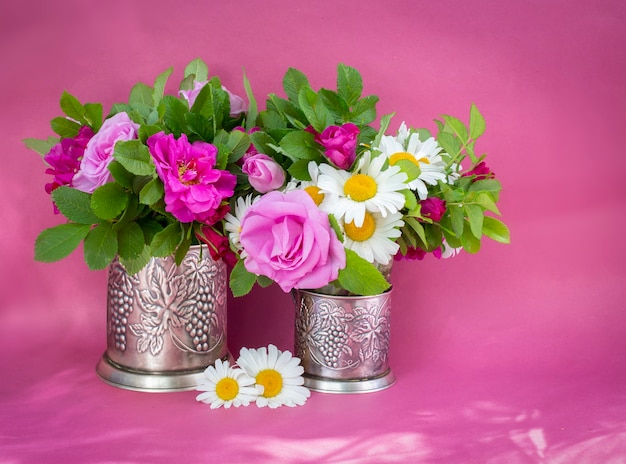 Rozenbottel roos en kamille boeket. Zomerboeket van tuinbloemen. Stilleven op de roze achtergrond