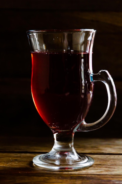 Rozenbottel thee in een glazen beker op een houten ondergrond.
