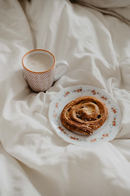 Foto rozijnenwerveling en koffie op wit bed