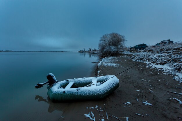 Rubber boat in the snow on the river bank