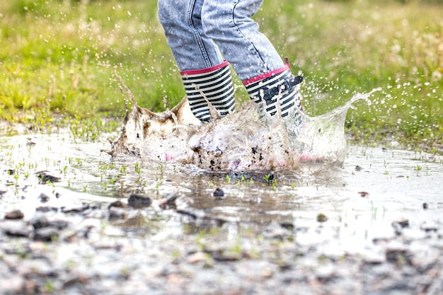 写真 水しぶきでジャンプする過程で水たまりにゴム長靴がクローズアップ。