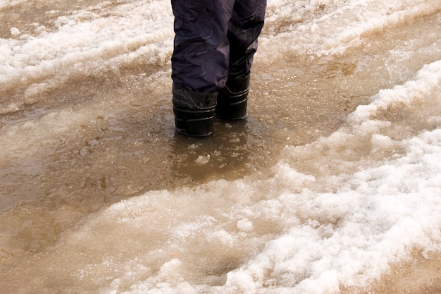 雨天時の街の水たまりにゴム製のブーツ。雨、雪、雹、街では信頼できる靴を履いて歩く方が良いです