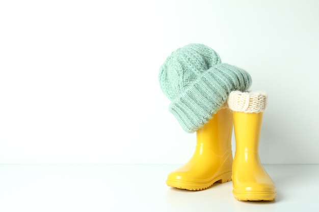 Rubber boots with knitted hat on white background.