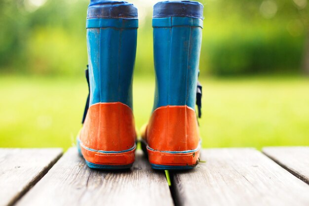 Rubber boots on a wooden background children's rubber boots on a background of green grass