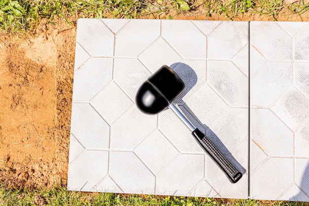 Rubber construction hammer for laying paving or garden tiles in\
the country cottage lies on a white stone slab concept of\
construction works