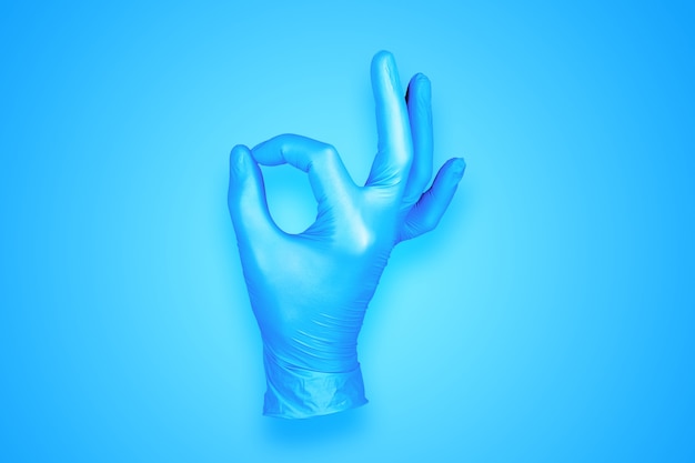 Фото Резиновая перчатка ок жест рукой, изолированные на синем фоне