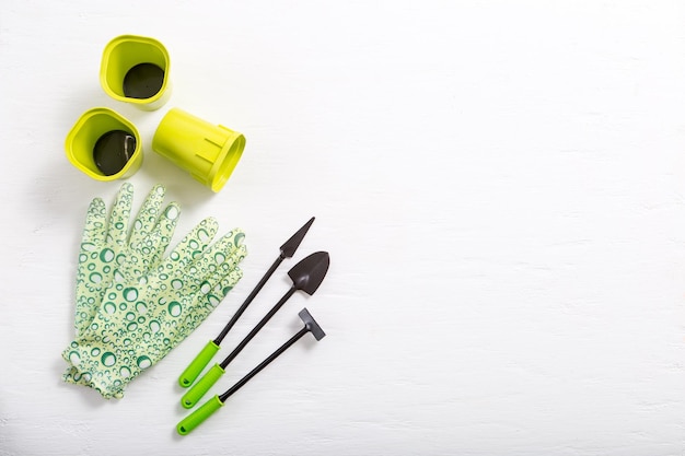 Rubber gloves and garden tools on white background. Preparation for the planting season. Selective focus.