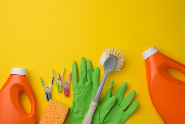 Rubber green gloves for cleaning, orange plastic bottle with detergent, brush 