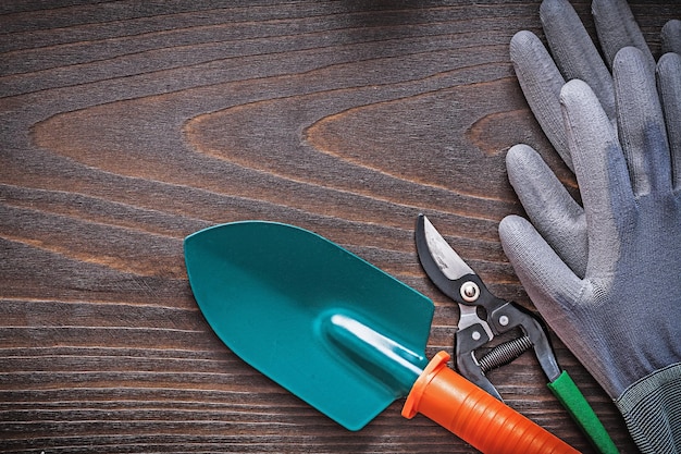 Rubber protective gloves hand shovel and secateurs on vintage wooden background agriculture concept