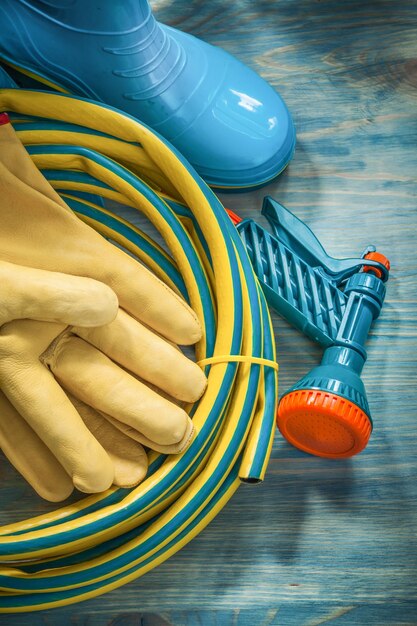 Rubber waterdichte laarzen lederen beschermende handschoenen tuinslang op houten plank tuinieren concept