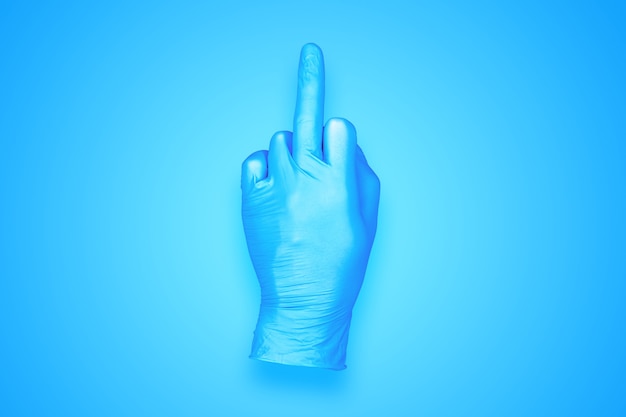 Rubberhandschoen die middelvingerhandgebaar doet dat op blauwe achtergrond wordt geïsoleerd