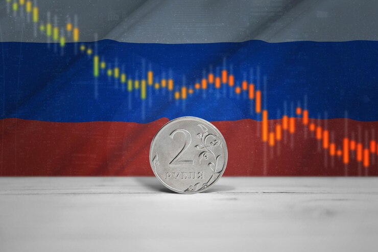 Рублевая монета на столе График падения и празднования российской валюты на российском флаге на заднем плане