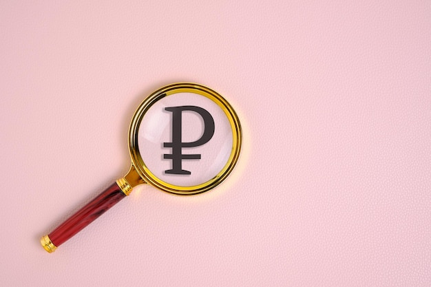 Ruble symbol under magnifying glass on pink background