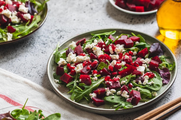 Rucola Bieten en kaas salade met granaatappel en dressing op plaat op grijze stenen keukentafel achtergrond plaats voor tekst bovenaanzicht