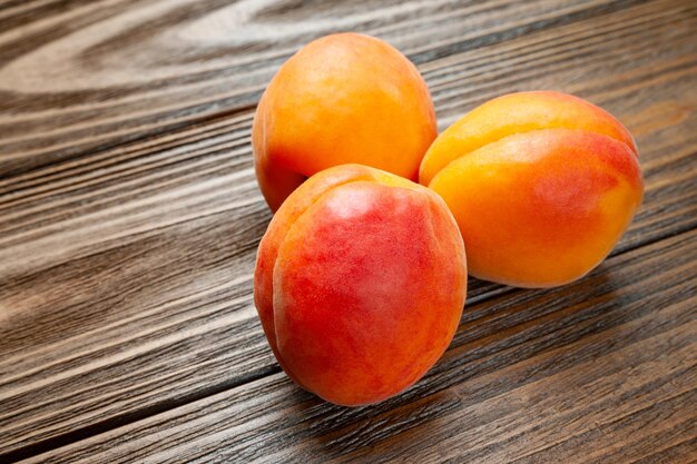 Ruddy apricots on a wooden background Three fresh juicy apricots piled on a wooden table