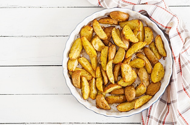Ruddy Baked potato wedges with garlic on a white background. 