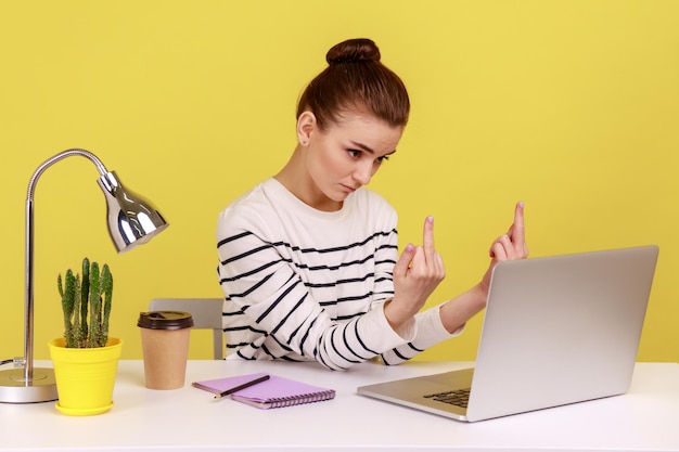 Rude woman showing middle finger to laptop screen aggressively communicating on video call