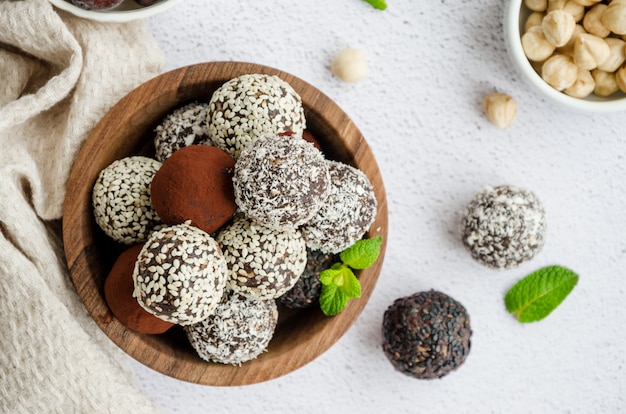 Photo ruffles of dates, walnuts, hazelnuts and cocoa in a wooden bowl on a light table