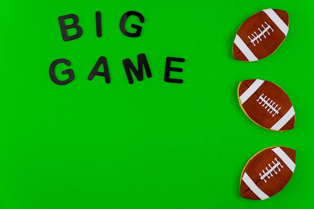 Photo rugby ball cookie with text big game on green background. american football background.