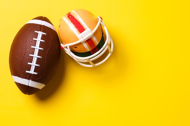 Rugby ball with helmet on yellow background with copy space