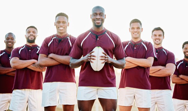 Campo da rugby e ritratto di squadra con palla e sorriso in piedi insieme con fiducia nel gioco vincente diversità uomo di colore e gruppo di uomini sportivi forti nella forma fisica della leadership e nel lavoro di squadra felice