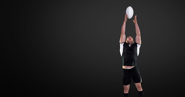 Rugby player jumping for ball with blank black background