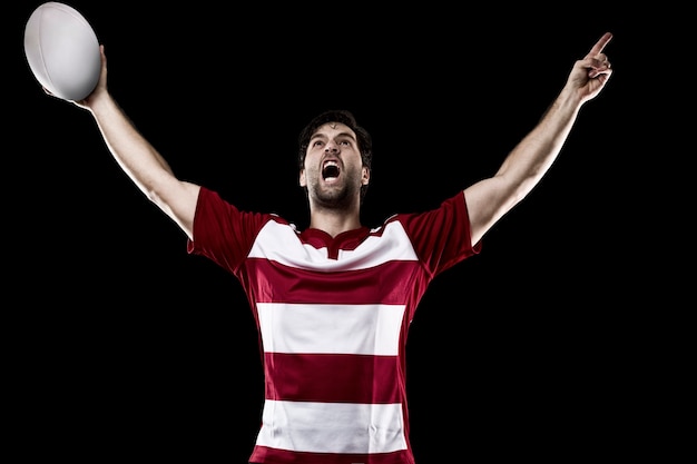 Rugby player in a red uniform celebrating. Black wall