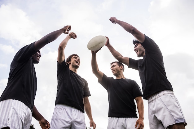 Rugby players cheering together with ball