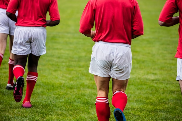 Rugby players jogging with ball