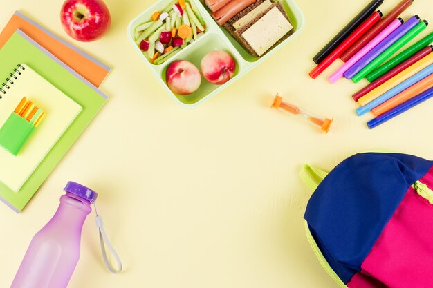 Rugzak, schoollunchbox en briefpapier op pastel bureaublad, kopie ruimte