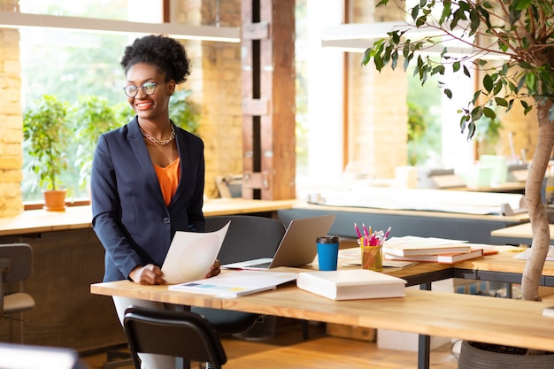 Ruime coworking. Binnenhuisarchitect die oranje blouse draagt die in ruime prettige coworking werkt