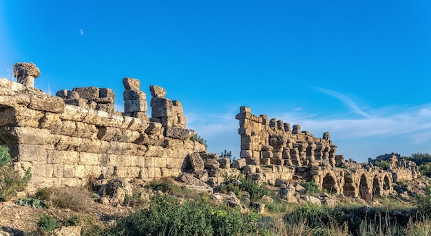 Ruïnes van oude stadsmuren tegen de achtergrond van de hemel met maan in Side, Turkije