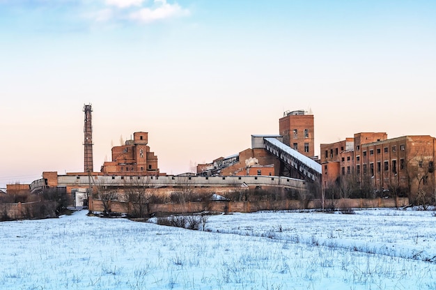 Ruins of abandoned factory in winter at sunset