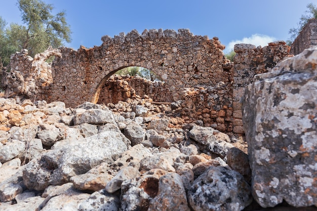 Ruins of an ancient building with a facade wall surrounded by heaps of stones, Crete, Greece