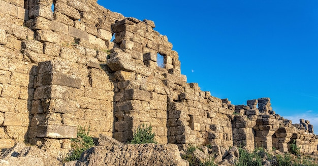 Ruins of ancient city walls against the backdrop of the moon in Side, Turkey