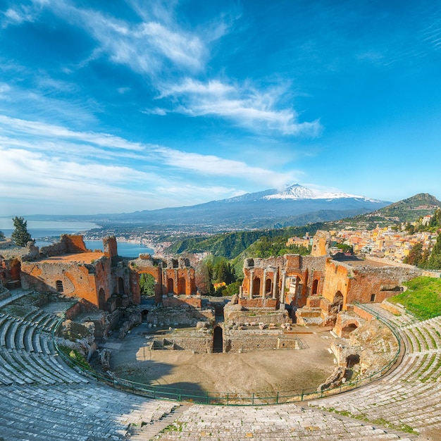 Foto rovine dell'antico teatro greco di taormina e sullo sfondo il vulcano etna