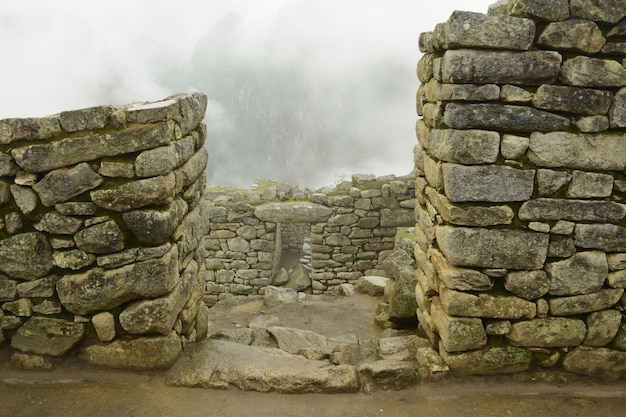 Ruins of the ancient Inca city machu picchu in fog Peru