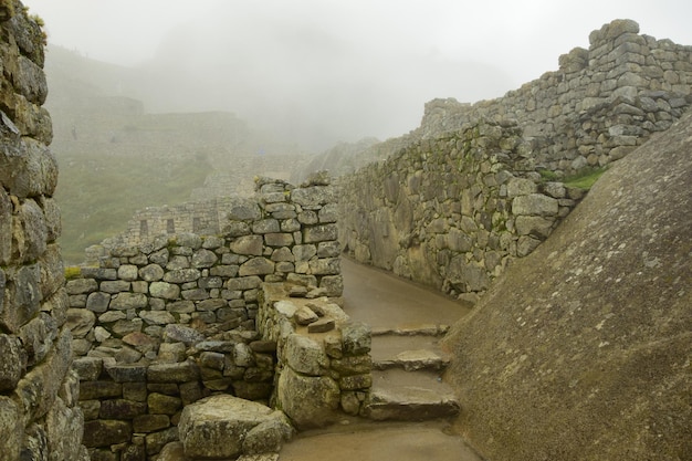 Ruins of the ancient Inca city machu picchu in fog Peru