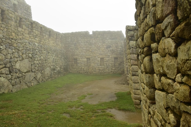 Ruins of the ancient Inca city machu picchu in fog Peru