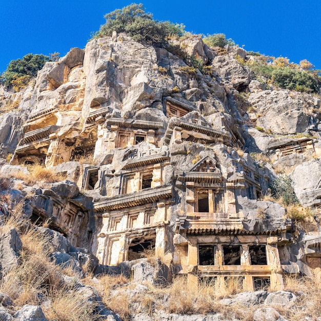 Ruins of a rocky necropolis with tombs carved in stone in Myra Lycian