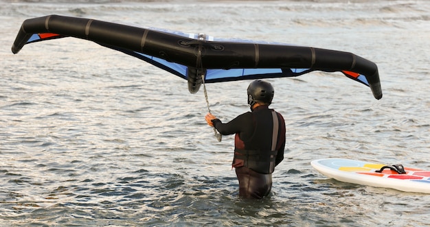Ruiter met complete uitrusting paddleboard en draagvleugelboot in het water