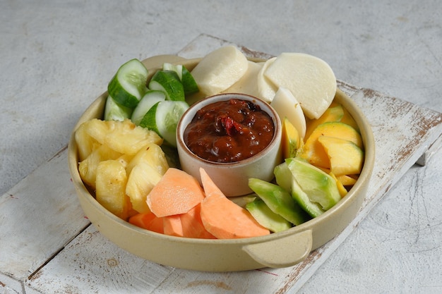 Rujak buah of indonesische fruitsalade op wit bord geserveerd met zoet pikante saus en gemalen pinda