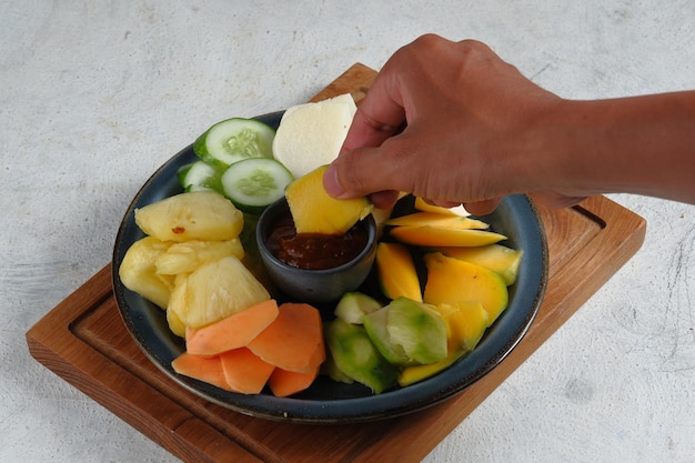 rujak buah of Indonesische fruitsalade op wit bord geserveerd met zoet pikante saus en gemalen pinda