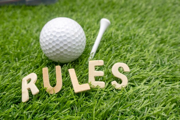 The rules of golf concept with golf ball and word of Rules are on green grass.