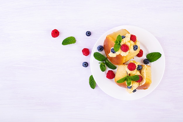 Rum savarian buns decorated with whipped cream and fresh berries