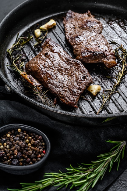 Rump steak in a frying pan. Grilled meat. Black background. Top view